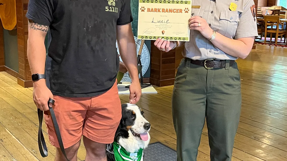 Park Ranger Posing with Canine BARK Ranger and Owner Park ranger posing with an owner and canine BARK Ranger during national park event